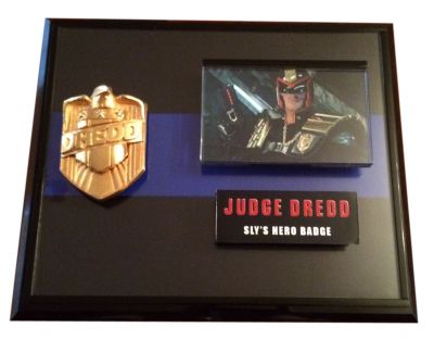 Judge Dredd's (Slyvester Stallone) Badge
Framed for the murder of a journalist, Judge John Dredd (Sylvester Stallone) is convicted to life in prison while his brother Rico (Armand Assante), presumed dead, takes control of the streets of Mega City One. Can Dredd reclaim his freedom, prove his innocence and save the city from the evil ex-Judge? This is a screen used Judge Dredd Police badge from the 1995 film, Judge Dredd. Used by Dredd as he patrolled the streets of Mega City One, dispensing his own, unique brand of justice. The metal badge features the ubiquitous Mega City One eagle and the crest of the Hall of Justice, with the name â€œDreddâ€ emblazoned across the middle. The badge has been gold plated and has a screw-back fitting for attaching it to Dreddâ€™s judge armor.
Keywords: Judge Dredd's (Slyvester Stallone) Badge